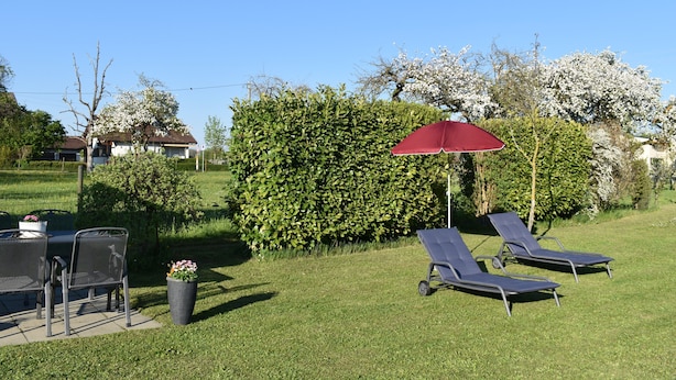 A patio with two lounge chairs and a table, surrounded by a well-maintained lawn and a hedge. - Apartment 'C' with Wi-Fi (Langenargen)