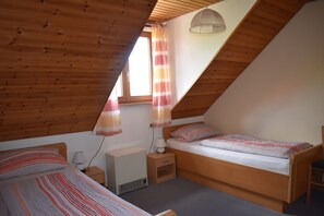 Une chambre avec deux lits, un radiateur, une lampe et une fenêtre avec des rideaux.