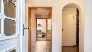 Un pasillo con una puerta de madera que da a una sala de estar con un sofá y una mesa de centro.
