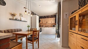 Una cocina moderna con armarios de madera, un comedor con mesa y sillas, y un horno empotrado.
