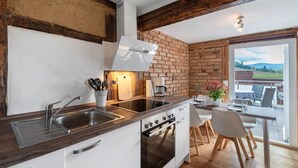A kitchen with a sink, stove, and dining area with chairs and a table.