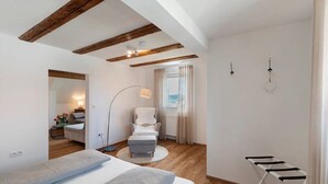 A bedroom with a bed, a chair, a desk, and a window with curtains.