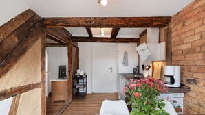 A rustic kitchen with exposed beams, a coffee machine, and a dining area with a table set for two.