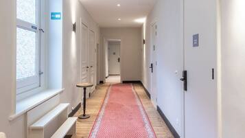 Pasillo de hotel con alfombra roja, paredes blancas y puertas numeradas 22.