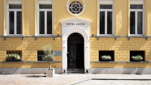 Un edificio amarillo con un cartel que dice 'HOTEL LUCCA' sobre la entrada.