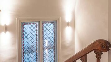 A wooden staircase with a handrail, a patterned rug, and a window with a grid design.