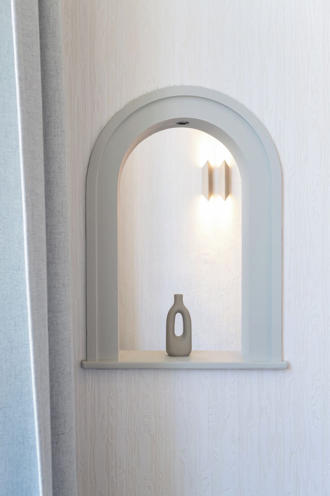 A white arched window with a small vase inside.