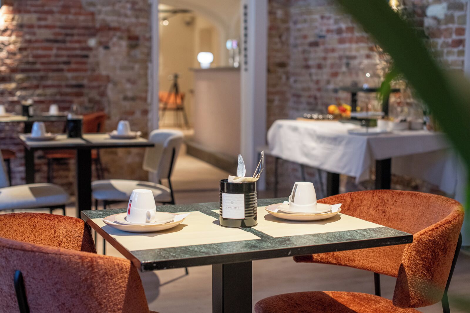 A restaurant setting with tables and chairs, a coffee machine, and a menu stand.