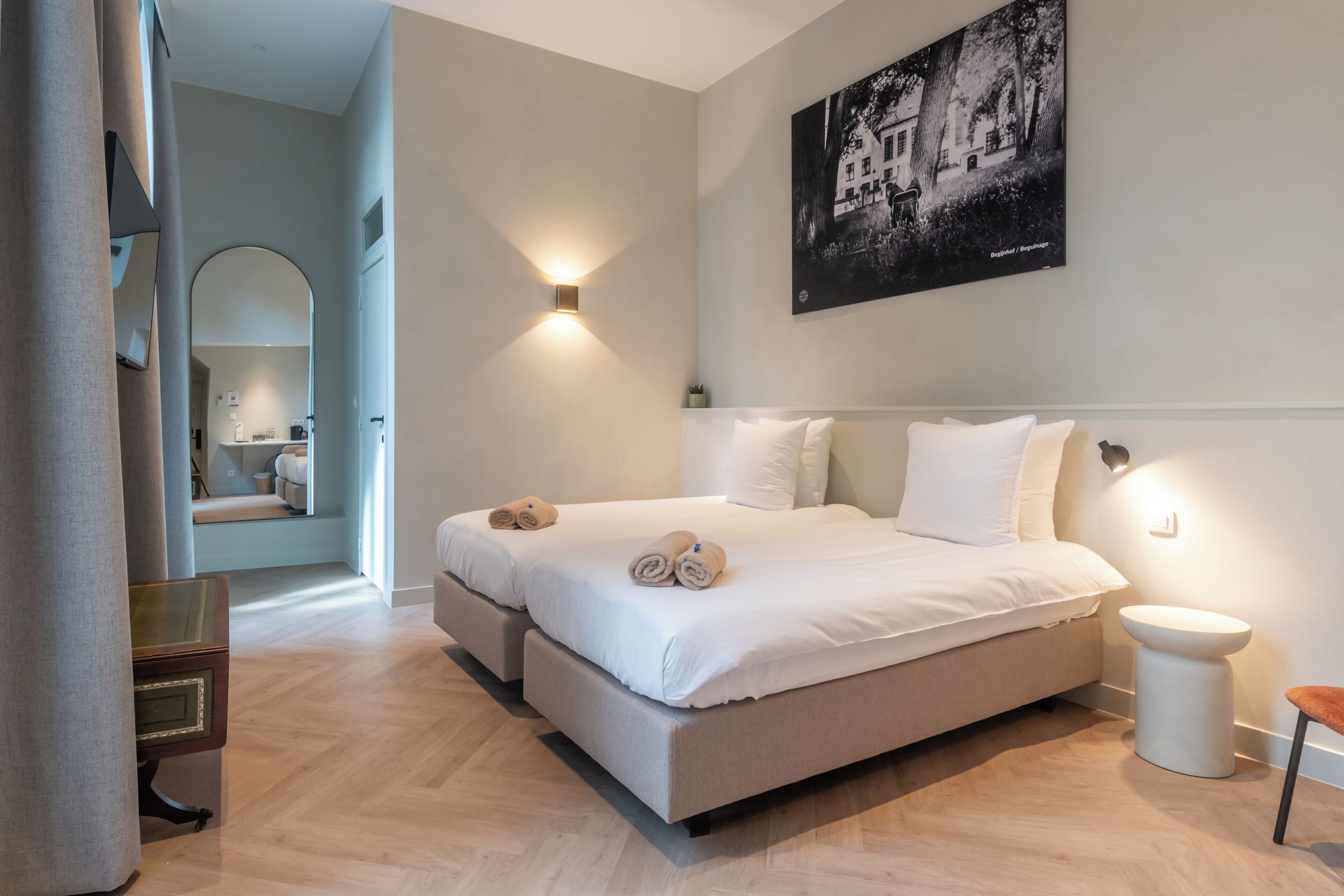 Een moderne slaapkamer met een groot bed, nachtlampjes, een schilderij en uitzicht op een badkamer.
