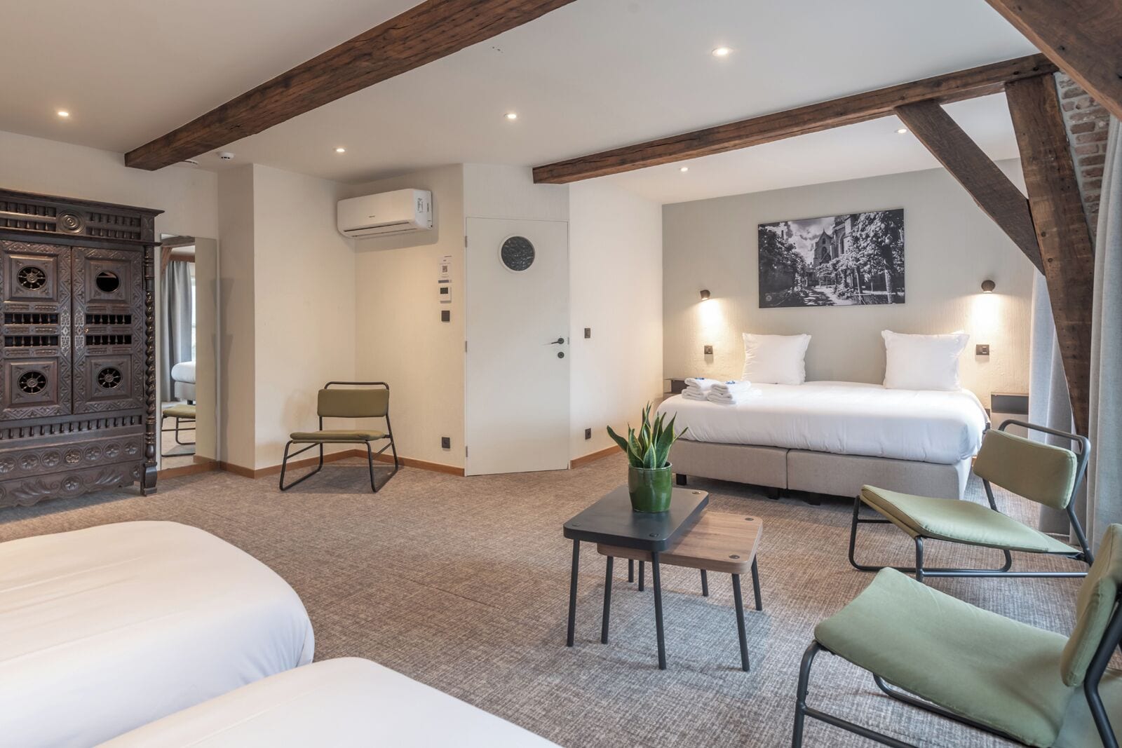 Una habitación de hotel con una cama, un escritorio, una silla y un aparador decorativo.