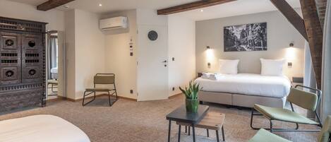 Una habitación de hotel con una cama, un escritorio, una silla y un aparador decorativo.