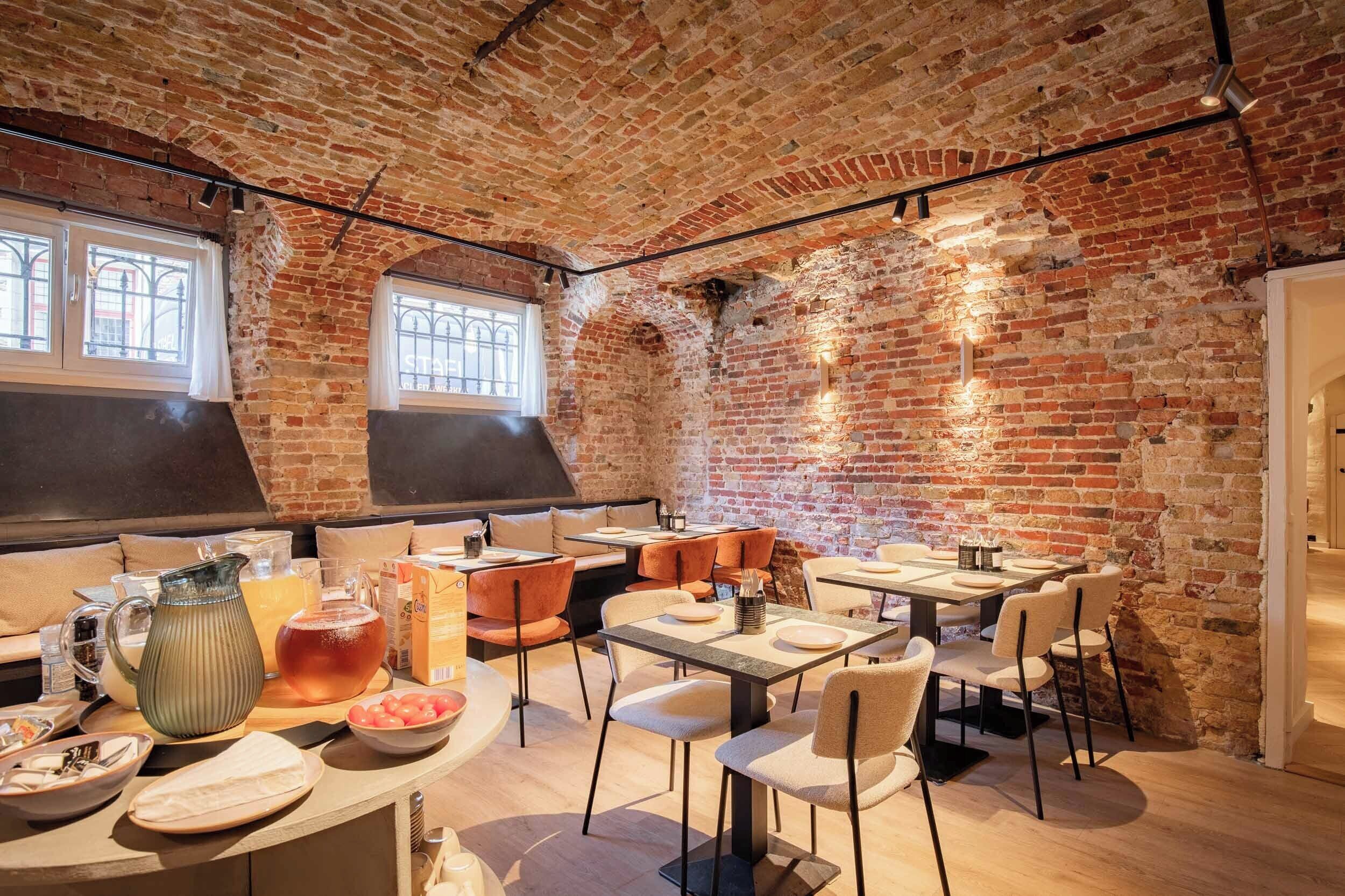 A restaurant with brick walls, wooden tables, and cushioned seating.