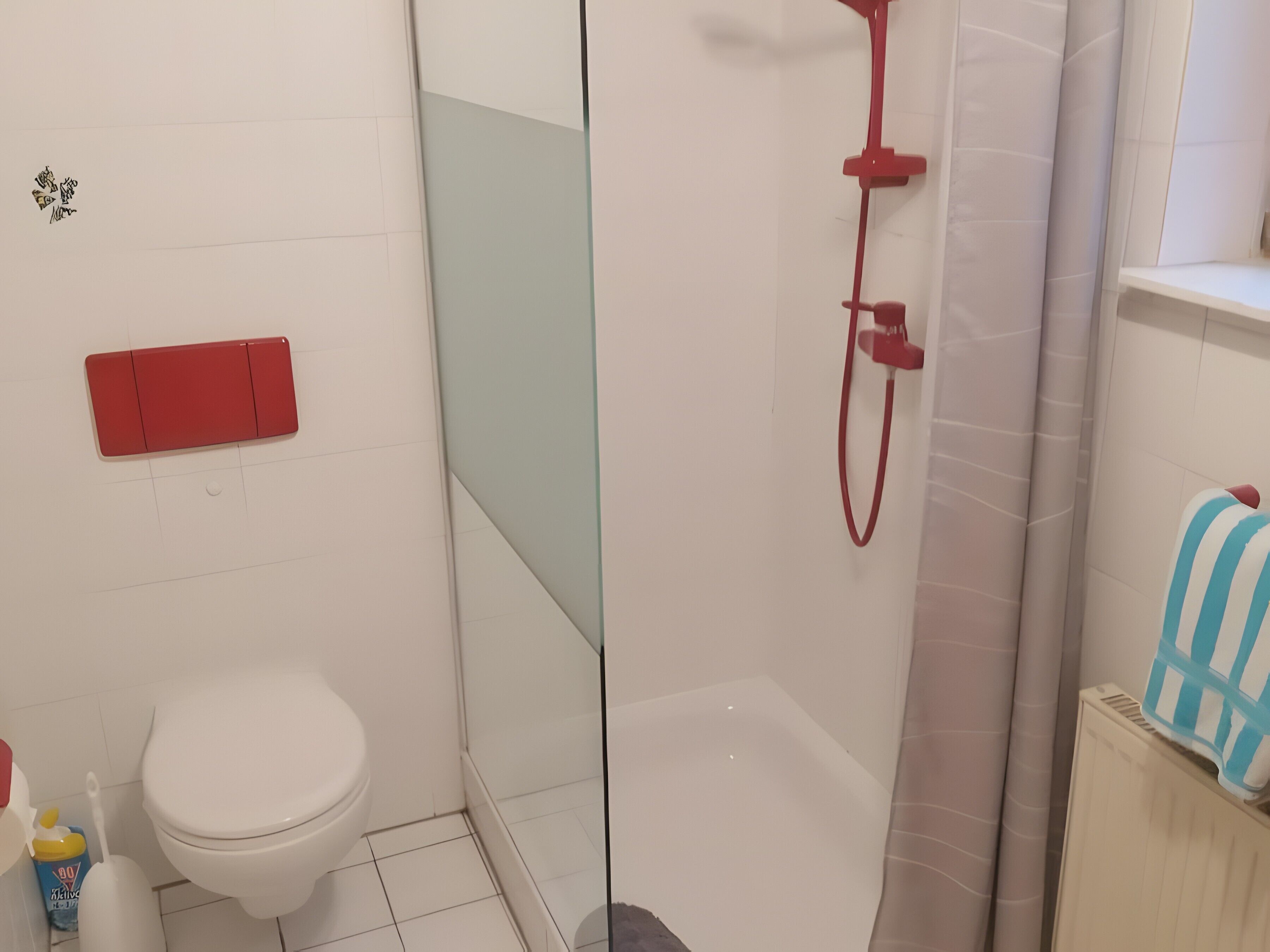 Ein Badezimmer mit Toilette, einer Duschkabine und einem Handtuchhalter.