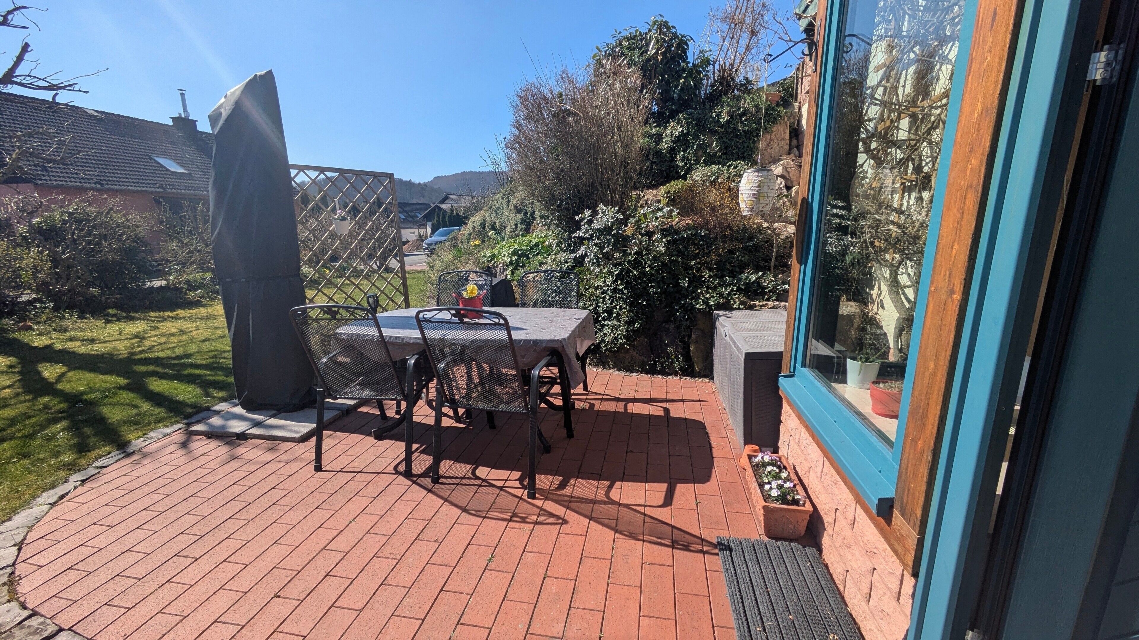 Un patio con tavolo e sedie, un pilastro in pietra e vista su un giardino e delle colline.