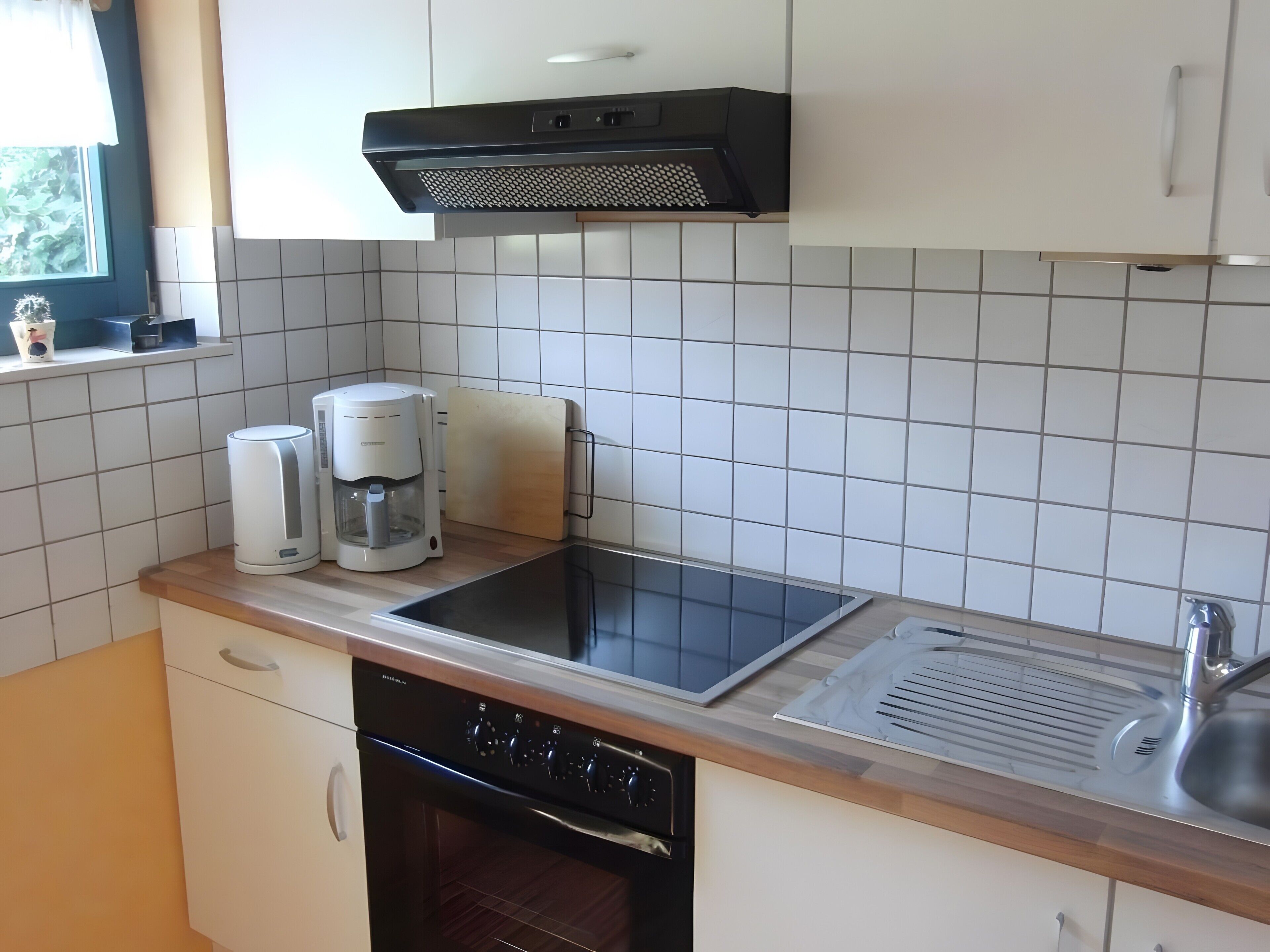 A kitchen with a built-in oven, a coffee maker, a toaster, and a sink.