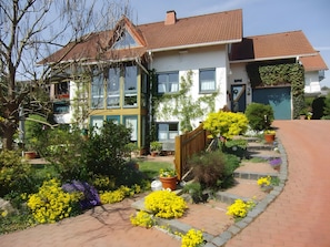 A two-story house with a garden, a wooden fence, and a garage. - Apartment 'Rösner' with Private Terrace, Shared Garden and Wi-Fi (Vöhl)
