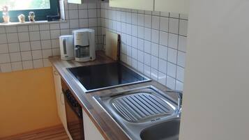 Une cuisine équipée d’une cuisinière intégrée, d’un évier et d’une fenêtre agrémentée de plantes en pot.