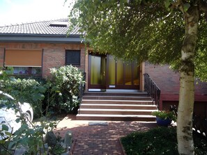 A brick building with a front entrance, steps, and a small garden area. - Apartment 'Drescher' with Shared Garden, Balcony and Wi-Fi (Cuxhaven)