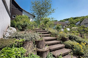Una zona residencial con una escalera de piedra que lleva a una casa, rodeada de vegetación y otras casas al fondo.