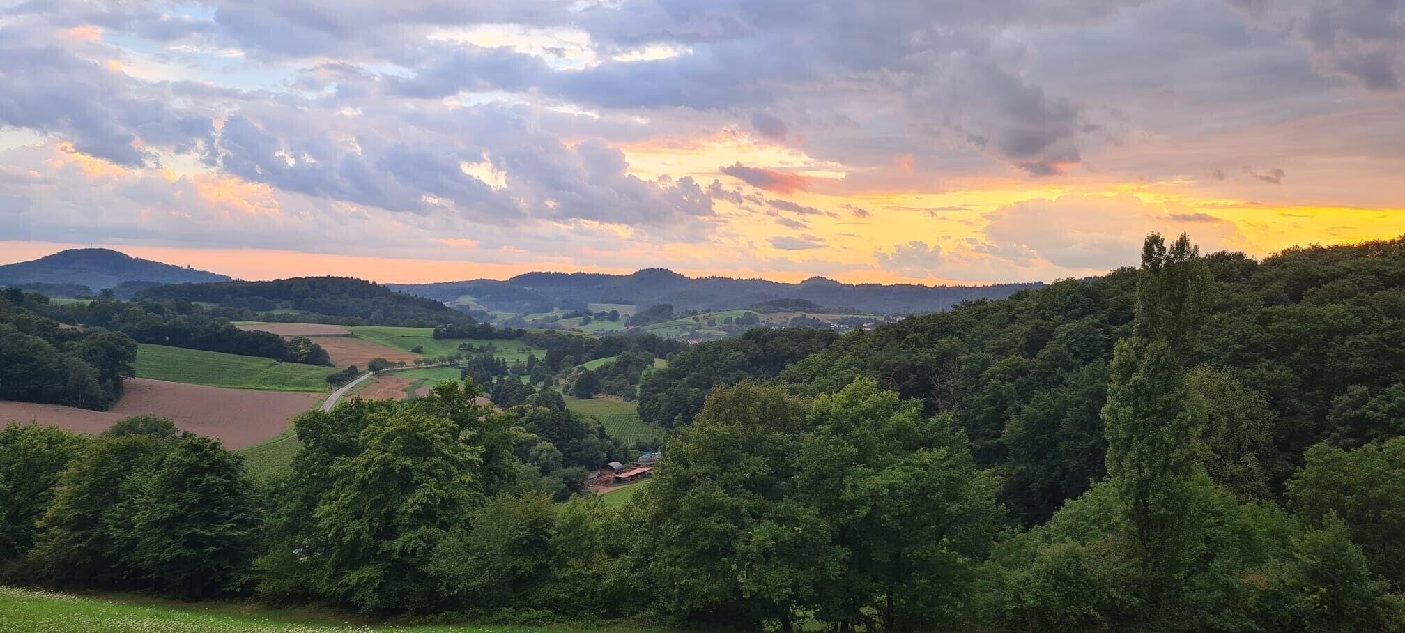 A landscape with rolling hills, fields, and a small settlement.