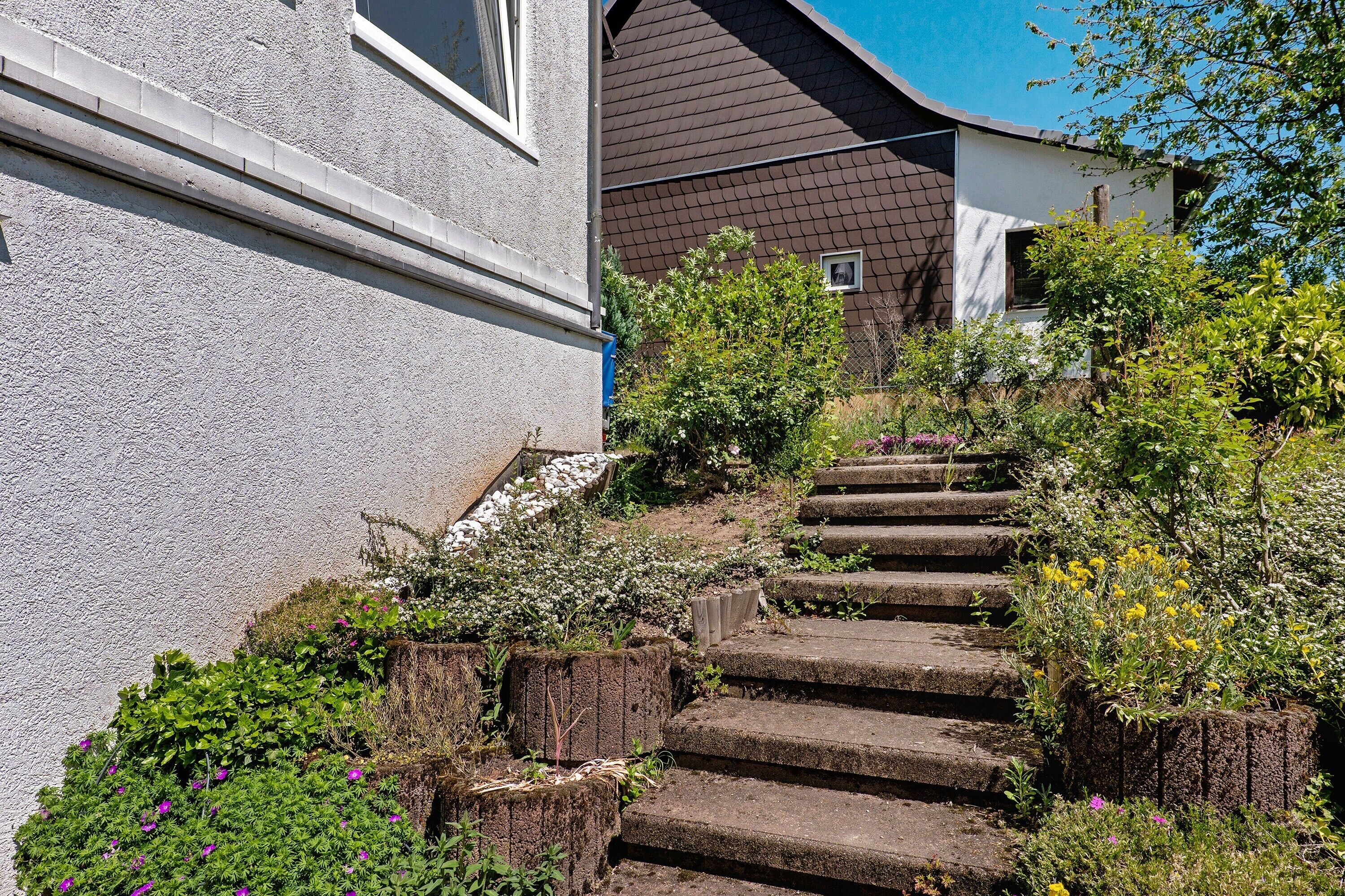 A staircase leading up to a house with a white exterior and a brown roof.