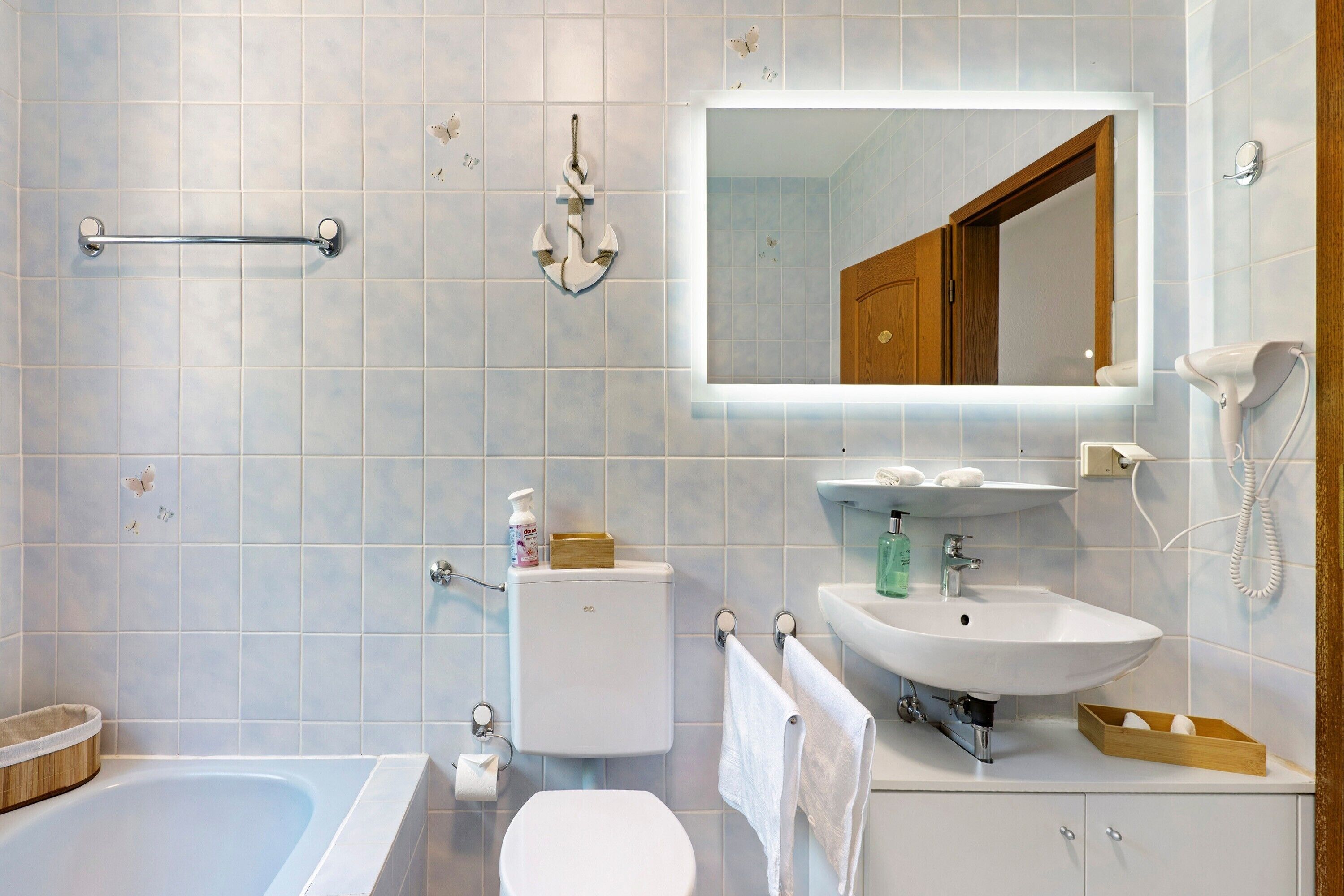 A bathroom with a bathtub, toilet, sink, and mirror.