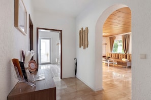 Un pasillo que conduce a una sala de estar con piso de madera, un sofá y una mesa de centro.