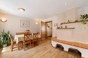 A dining area with a wooden table and chairs, a bench, a potted plant, and a kitchen visible through an open door. - Holiday Home 'Becker' with Private Terrace, Private Garden and Wi-Fi (Schönau (Pfalz))