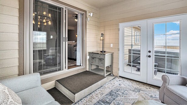 A covered porch with a sliding glass door, a small table with drawers, and a rug. - Ayu Ranch | Panoramic views | Hot tub (Cheyenne)