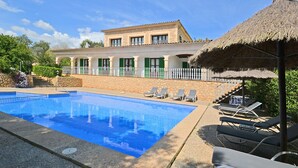 A swimming pool with lounge chairs and a building with green shutters. - Pleta - Rustic villa in Petra with private pool and beautiful views (Petra)