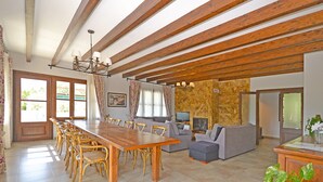 A spacious living area with a wooden dining table and chairs, a sofa, and a television. - Pleta - Rustic villa in Petra with private pool and beautiful views (Petra)