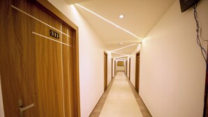 Pasillo de hotel con puertas de madera, placas con números de habitación y suelo de baldosas.