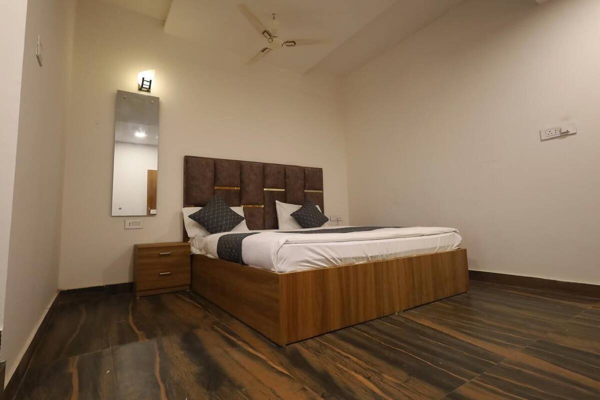 A bedroom with a wooden bed, a nightstand, a mirror, and a ceiling fan.