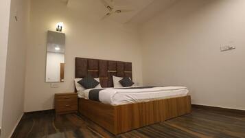 A bedroom with a wooden bed, a nightstand, a mirror, and a ceiling fan.