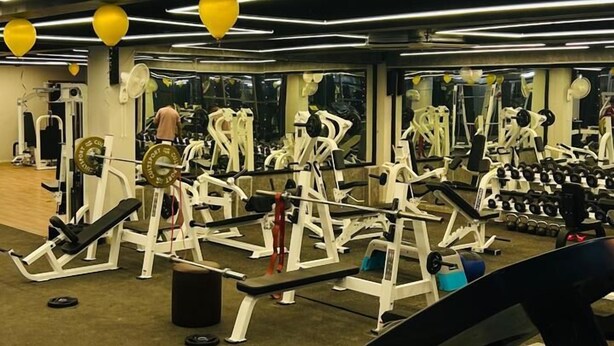 Un gimnasio con diversos equipos de ejercicio, como cintas de correr y máquinas de pesas.