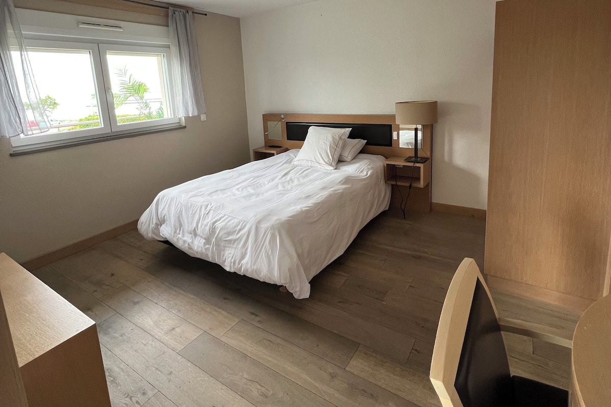 Une chambre à coucher avec un lit, des tables de chevet, une chaise et une fenêtre.