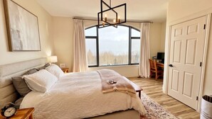 A bedroom with a bed, a desk, a chair, a window, and a door. - Ski-In/Out Mountain Escape with Hot Tub (Kimberley)