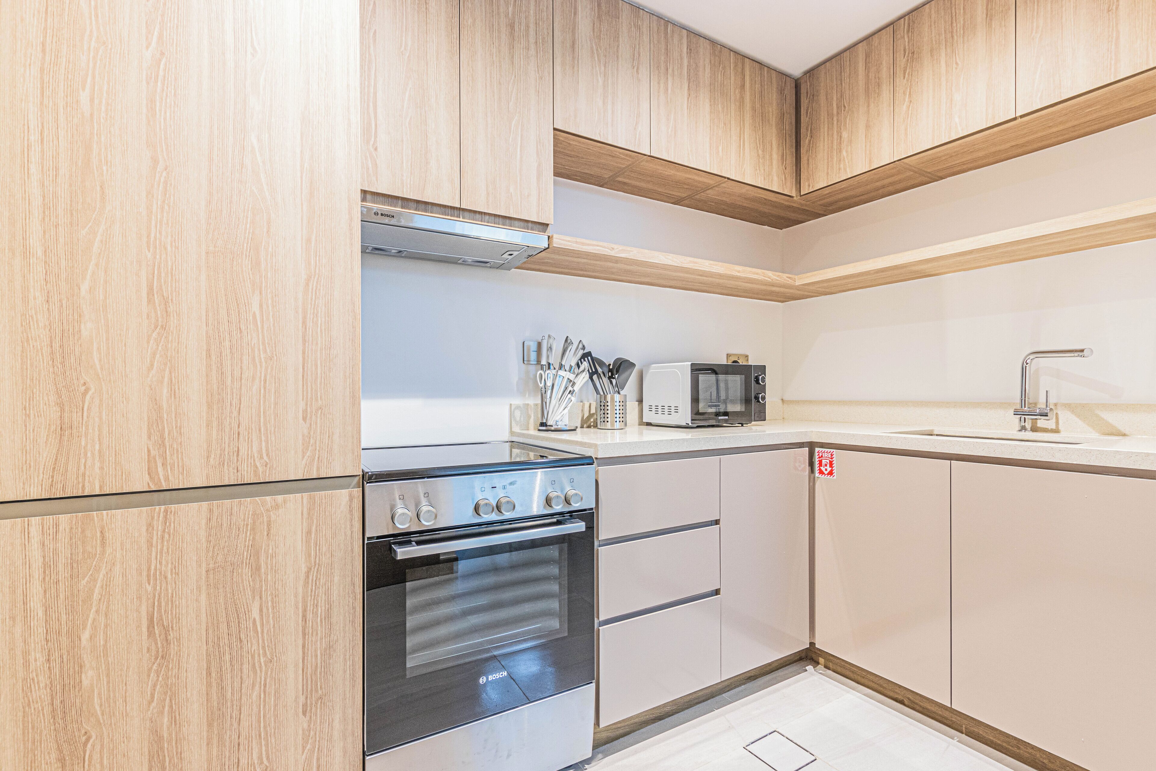 Eine moderne Küche mit Holzschränken, einem Edelstahlbackofen, einer Mikrowelle und einem Spülbecken.