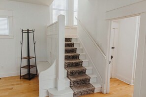 Eine Treppe mit weißer Handläufe und gemustertem Teppich, die zu einer Tür führt.
