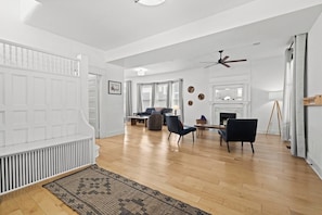 Un vaste espace de vie doté d’une cheminée, de sièges confortables et d’un ventilateur de plafond.