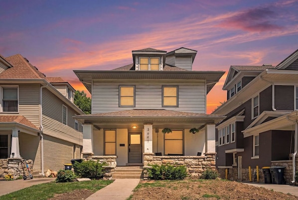 A two-story house with a front porch, stone foundation, and a number '364' sign.