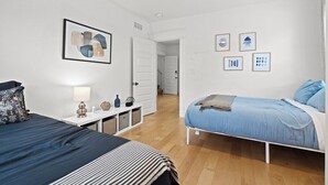 Une chambre avec deux lits, un ventilateur de plafond blanc et une porte donnant sur une autre pièce.