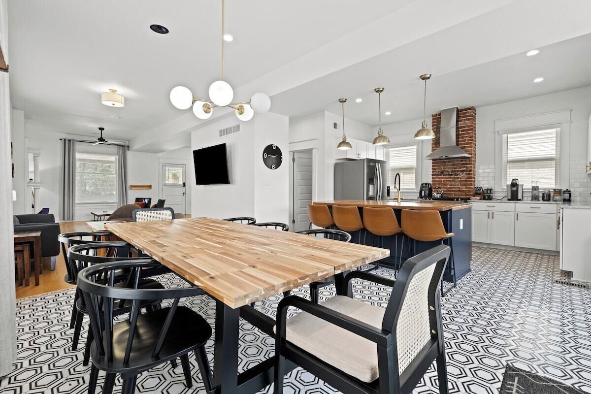 A modern kitchen with a wooden dining table, black chairs, and a brick oven.