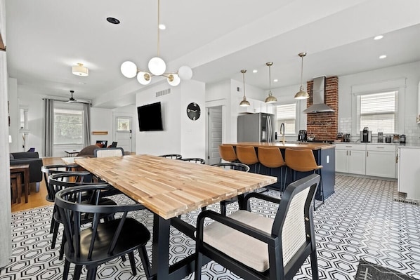 Una cocina moderna con una mesa de comedor de madera, sillas negras y un horno de ladrillo.