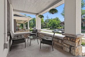 Un espace extérieur aménagé en terrasse, avec des meubles en osier et des jardinières suspendues.