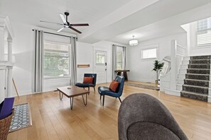 Un vaste espace de vie doté d’un ventilateur de plafond, d’un escalier et d’une table à manger.