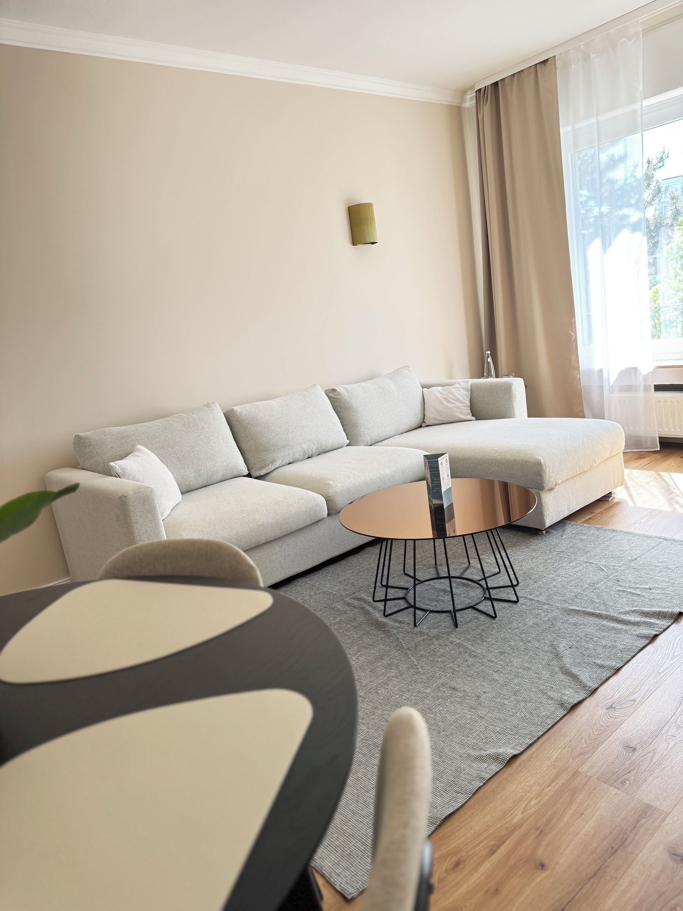 Una sala de estar moderna con un sofá modular, una mesa de centro redonda y una alfombra gris.