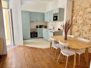 A kitchen with light blue cabinets, a microwave, a sink, and a dining table with white chairs.