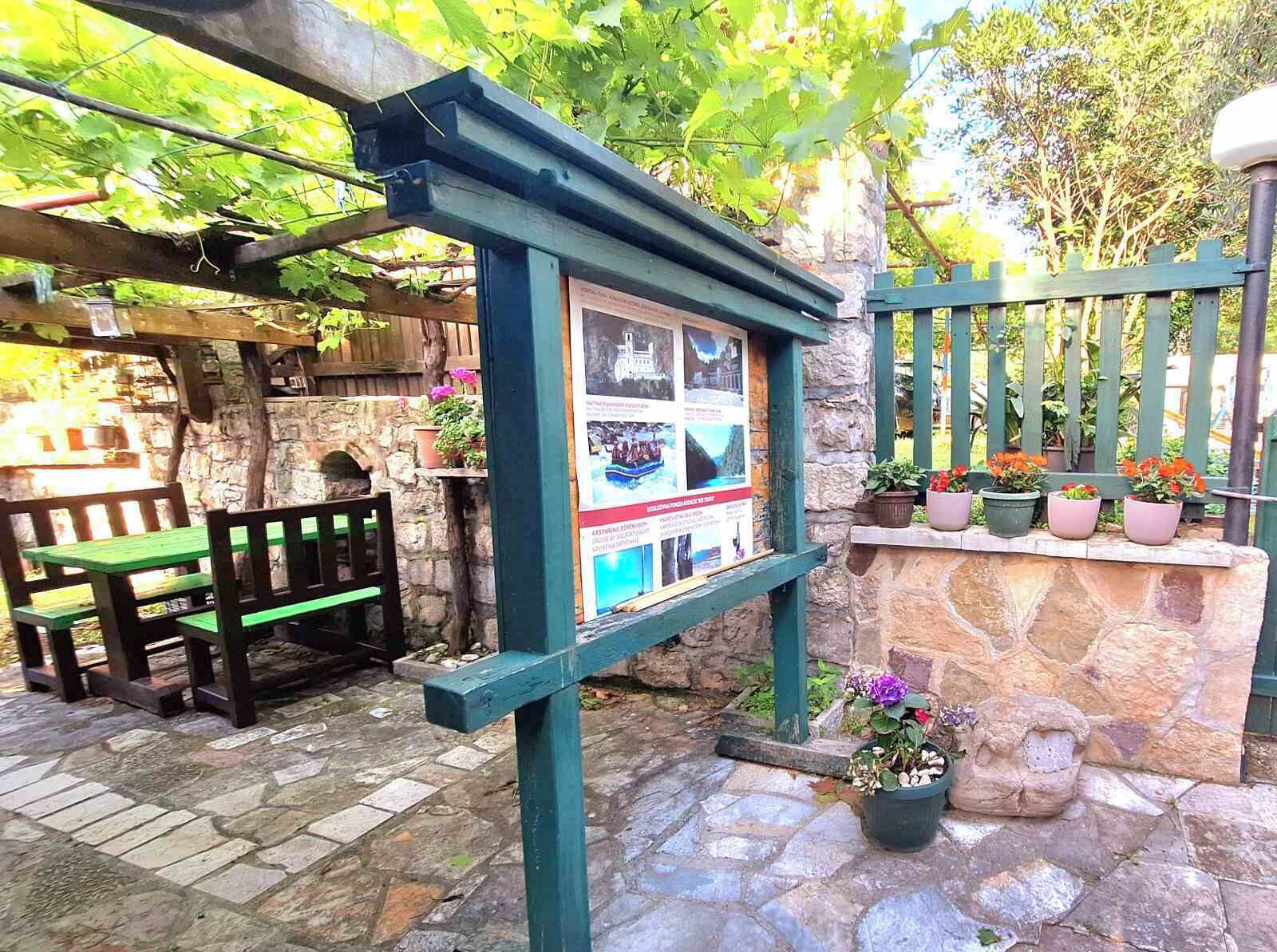 Um pátio de pedra com um banco de madeira e uma pérgola.