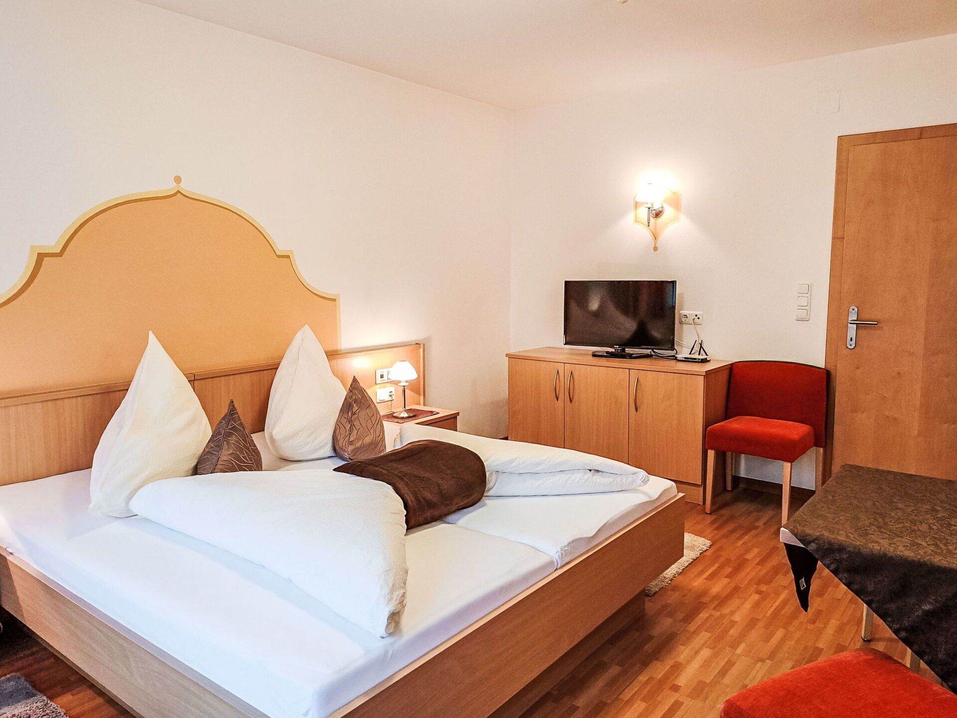Ein Hotelzimmer mit Bett, Fernseher, Schreibtisch und Stuhl.